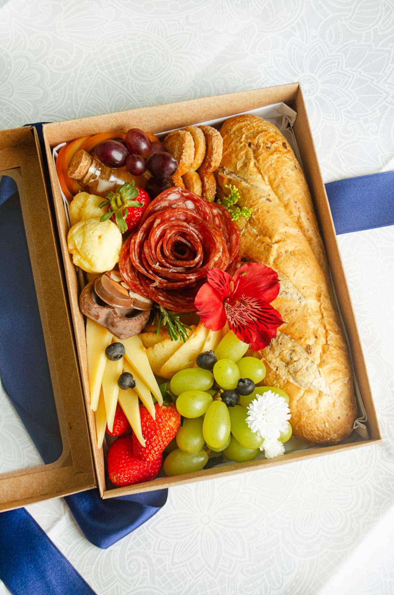 Café na Caixa Individual em caixa craft com baguete artesanal, flor de salame, queijos, uvas e morangos.