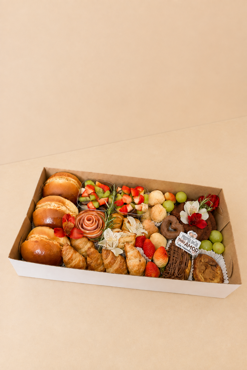 Café na Caixa em caixa craft com pães brioche, croissants, salada de frutas, flor de presunto e doces.
