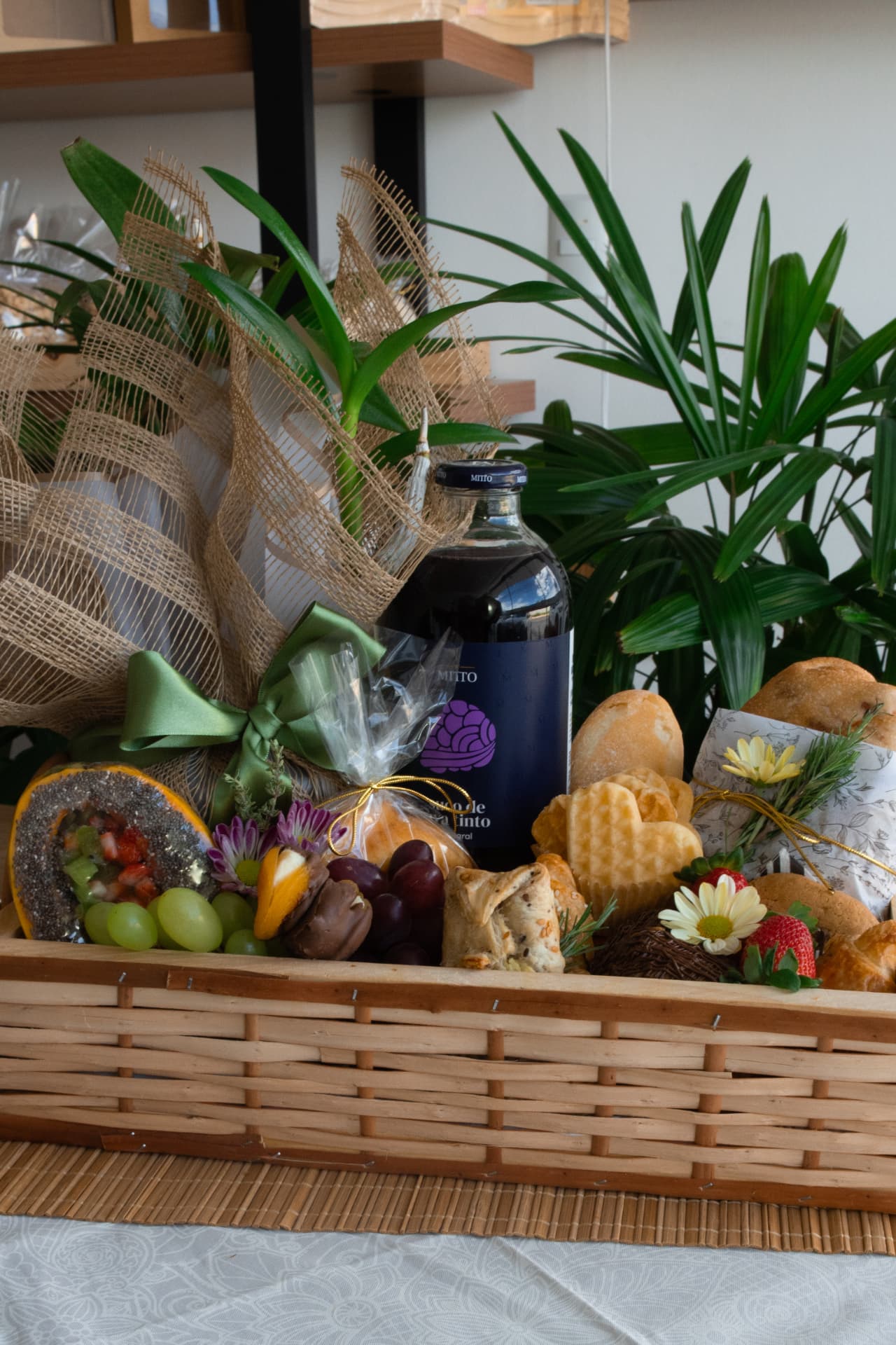 Cesta Amor que Aquece em bandeja de vime com suco integral, pães, frutas e doces.