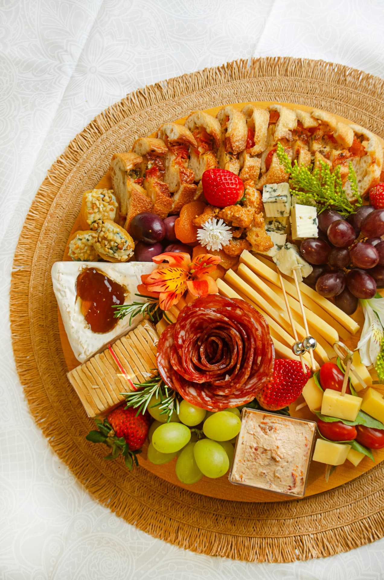 Cesta de Charcutaria com queijos, flor de salame, uvas, morangos e baguete artesanal.